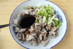 Kế đến, cho 1 muỗng canh nước tương và hành cắt nhỏ tô đựng bao tử. Thêm tỏi băm và 1/2 muỗng cà phê sa tế cùng ít mè trắng rang vào.