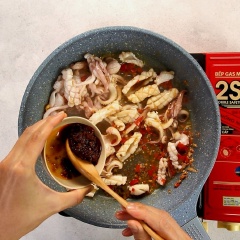 Nêm vào mực 1 muỗng canh nước mắm, 1 muỗng canh dầu hào, 1 muỗng canh sa tế, 1 muỗng canh đường, đảo nhanh tay và đều.