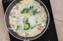 Phi thơm hành tím băm với 2 muỗng canh dầu ăn, cho trứng đã đánh vào dàn đều khoang 15-20 giây. Sau đó rải đều nấm rơm, nấm bào ngư, đậy vung khoảng 45-60 giây. Tiếp đến rải lên hành tây và hành lá, đậy vung đun nhỏ lửa cho trứng chín là được.