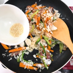 Sau khi xào thấm nguyên liệu, cho cơm nguội vào xào cùng. Nêm 1 muỗng canh hạt nêm vào. Xào đều lại một lần nữa để cơm thấm hết gia vị.