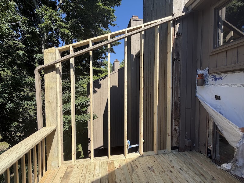 New balcony wall framing at The Lookout with the original dark siding and protective sheeting behind it