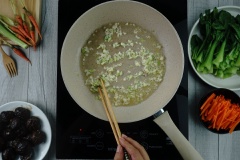 Tận dụng luôn chảo xào nấm, cho vào 3 muỗng canh dầu ăn. Vặn lửa lớn, cho hết phần đầu hành boarô và tỏi còn lại vào phi thơm. Cho cà rốt vào xào trước 2 phút (vì cà rốt lâu chín hơn cải), sau đó cho cải thìa và nấm vào cùng lúc. Nêm 3 muỗng canh dầu hào, 200 ml nước, 2 muỗng cà phê đường. Nhanh tay đảo đều chảo.