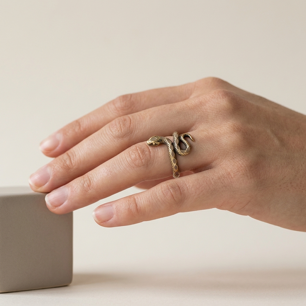 Side view of hand wearing an inward facing ouroboros snake ring showing fit and finger anatomy on pale beige background #ede7da