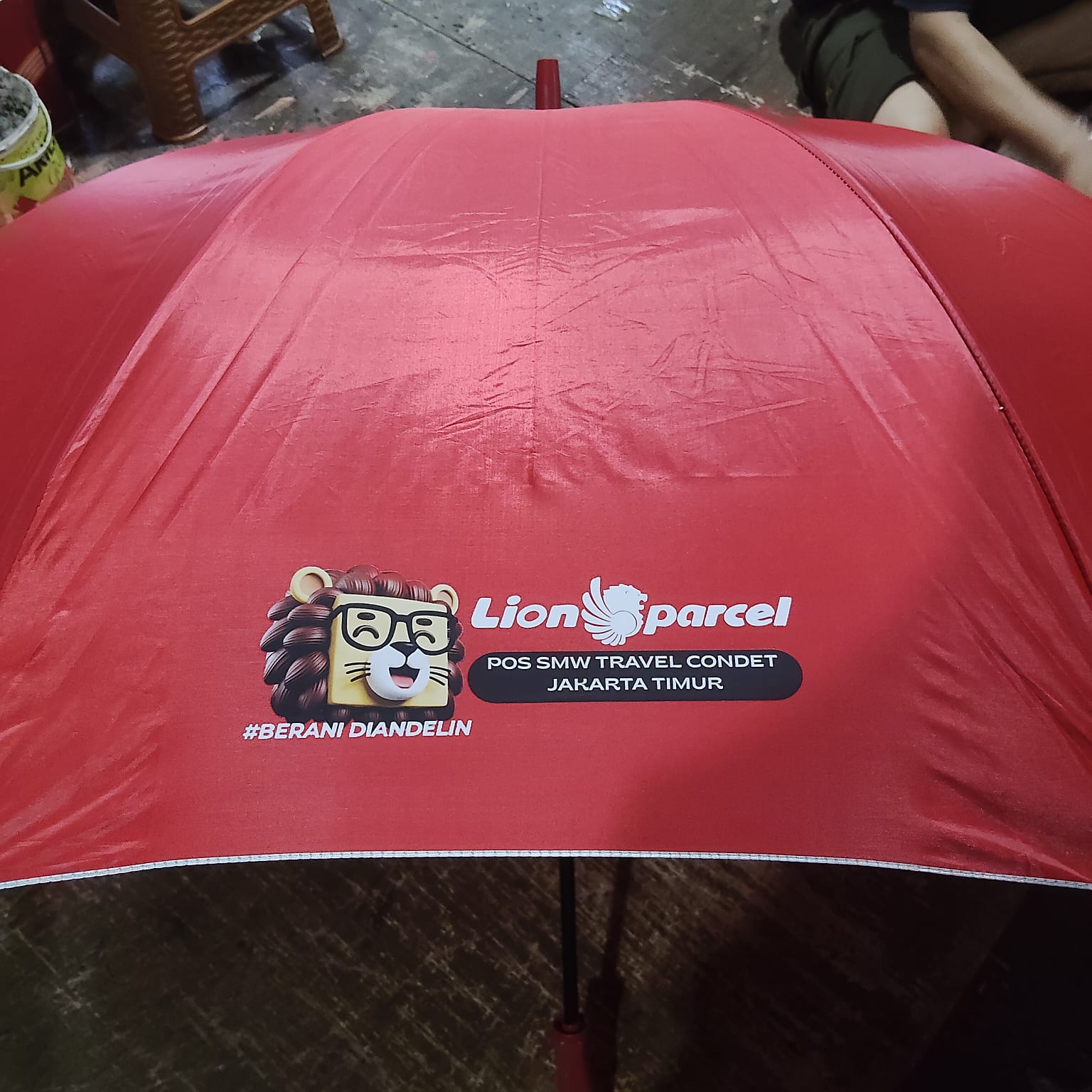 Payung custom merah dengan branding Lion Parcel — Sekar Printing