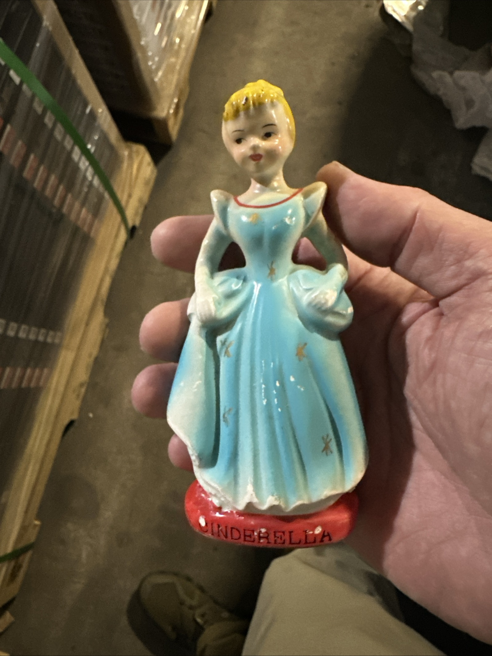 Mid-century ceramic Cinderella figurine in blue ball gown on red base, approximately 4–5 inches tall, showing paint wear consistent with age