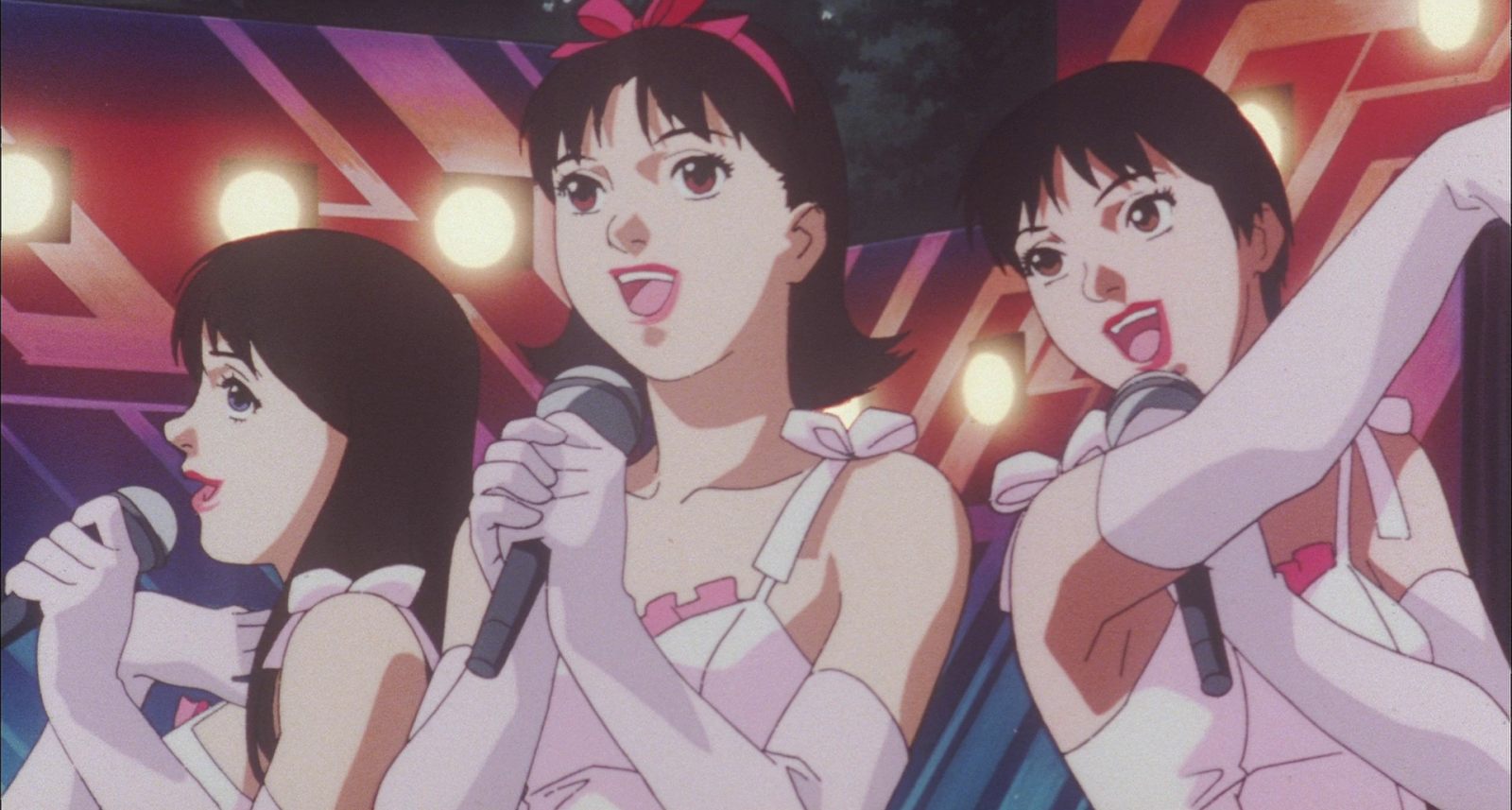 Mima and her CHAM! bandmates singing on stage in white dresses under stage lights