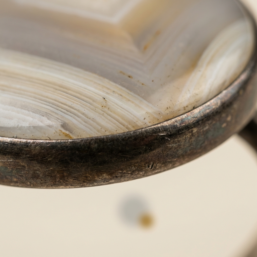 Macro studio photo of banded chalcedony bezel and patinated metal edge highlighting layering and texture on neutral background #ede7da black onyx roman soldier ring