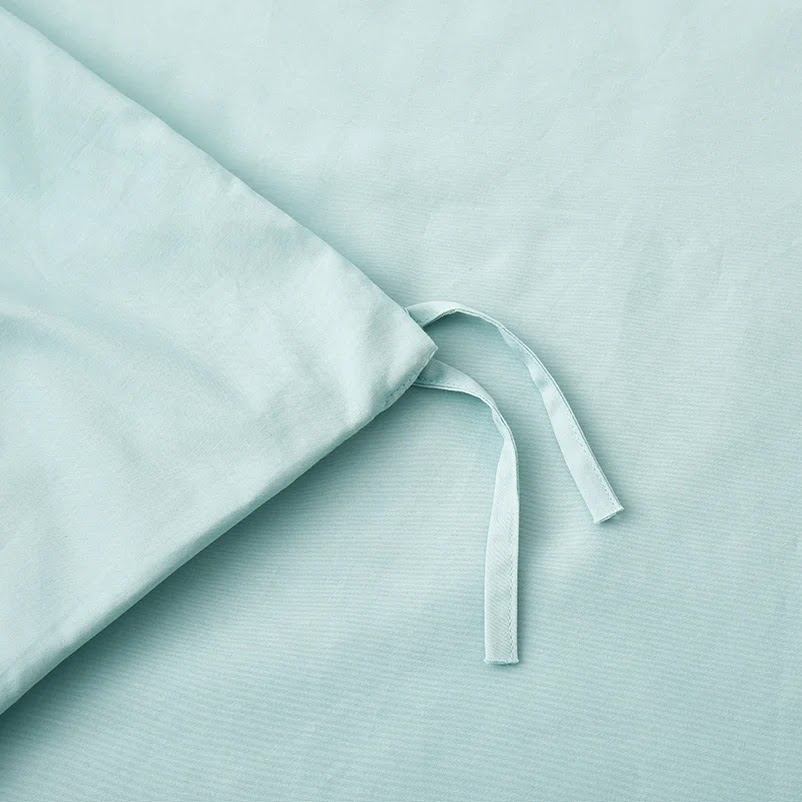 Close-up of a pale aqua cotton duvet cover corner showing the inner fabric tie