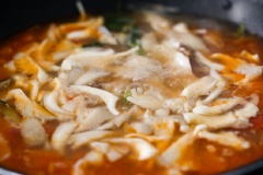 Bắc chảo dầu lên bếp, phi thơm hành tím, tỏi, cho cà chua đã thái hạt lựu vào xào từ 7-10 phút cho đến khi cà chua mềm, ra nước. Cho 1 lít nước vào một nồi lớn, đổ cà chua vào rồi đến khi sôi. Tiếp tục cho nấm, hành tây, cần tây vào nấu cùng khoảng 10 phút. Cuối cùng cho cá vào nấu thêm 1 lúc để cá chín, nêm lại gia vị rồi tắt bếp, rắc hành ngò là xong.