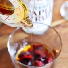 Thêm vào ly cherry lần lượt: Rượu, siro cây phong, tinh chất vani, nước cốt chanh. Dùng chày ấn nhẹ cho cherry dập và tiết ra nước.