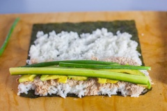 Hành lá rửa sạch, nhặt lấy phần xanh. Dưa leo, bơ thái nhỏ. Cá ngừ trộn với sốt mayonnaise. Khi cuộn, bạn trải lá rong biển ra, trải một ít cơm và tán thật đều lên rong biển, kết tiếp, bạn tán một lượng vừa đủ cá ngừ, lót thêm bơ, dưa leo và hành lá, cuốn chặt tay là hoàn thành