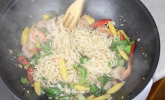Phi thơm tỏi băm với 2 muỗng canh dầu ăn, thêm vào tất cả các loại rau đã sơ chế, đảo đều khoảng 1 phút. Sau đó cho thêm 1 muỗng canh nước tương, 1 muỗng canh dầu hào, 100g tôm bóc vỏ và 1 muỗng cà phê đường. Khi tôm gần chín, thêm vào mì ăn liền, xào cho đến khi tôm chín, tắt lửa, cho vào lá húng quế và trộn đều là được.