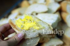 Bơ làm tan chảy. Quết đều bơ, rắc muối, tỏi băm, lá rosemary tươi lên từng lát bánh mì.