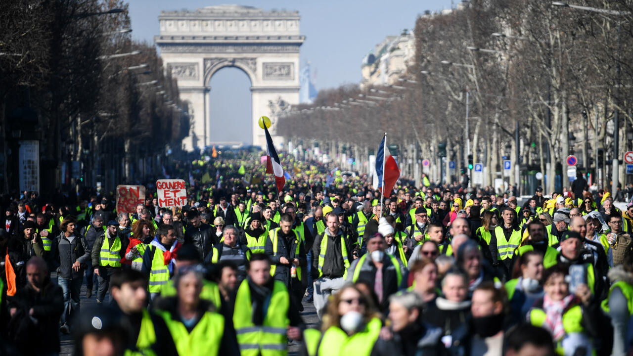 Protesters wearing green vests marching away from Arche de Triomphe