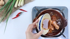 Khi gà săn lại, cho tiếp 30ml nước cốt me vào nồi, đậy nắp và kho gà ở lửa nhỏ trong khoảng 20 phút đến khi nước cạn lại, gà thấm gia vị. Sau đó rắc hành lá và tiêu xay lên trên mặt.