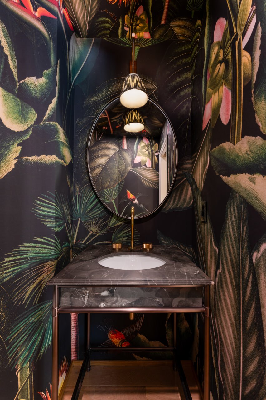 Powder room — dark botanical wallpaper, black marble vanity, brass fixtures — Kellow Construction