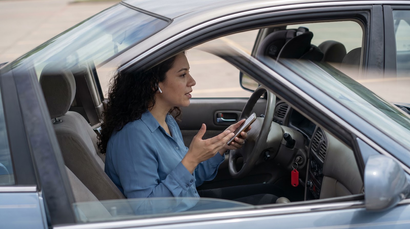 Hispanic Texas driver documenting evidence for a texas parking lot hit and run insurance claim from her car in a mall parking lot