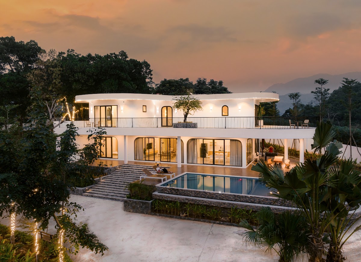 Villa tường trắng bo cong và bể bơi lên đèn lúc chạng vạng ở Gạc Nai Ba Vì