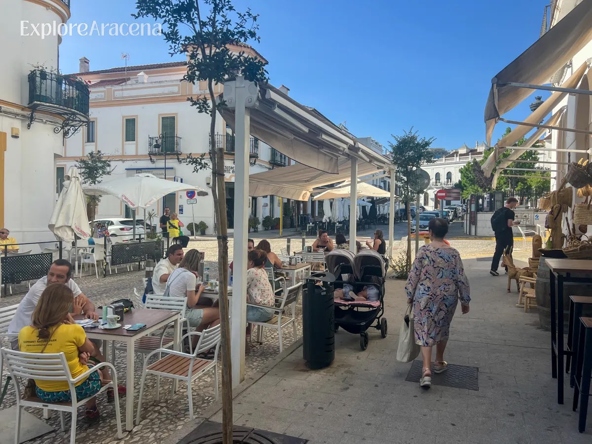 Local residents spending time on a street in Aracena, walking and enjoying coffee at outdoor cafés.