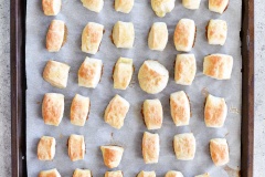 Bật trước lò nướng ở 425 độ F. Pha baking soda với nước, nhúng từng viên bột bánh bao vào hỗn hợp baking soda rồi trải lên khay nướng có lót sẵn giấy nến. Cho viên bánh bao vào lò nướng 7-10 phút. Sau đó lấy khay ra, phết bơ lên trên mặt bánh bao nướng, phủ thêm một ít đường, mè trắng, muối tùy thích là hoàn thành.