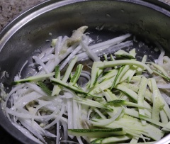 Cho lần lượt củ cải trắng cắt sợi, bí ngòi, củ hành, cà rốt cắt sợi vào đảo thật đều tay để rau củ chín đều.