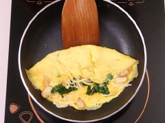 Tiếp theo, cho phô mai parmesan, cải bó xôi vào, gấp đôi miếng trứng lại, chiên thêm 1 phút.