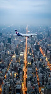 Commercial Airplane Flying Over Illuminated City Skyline Dusk