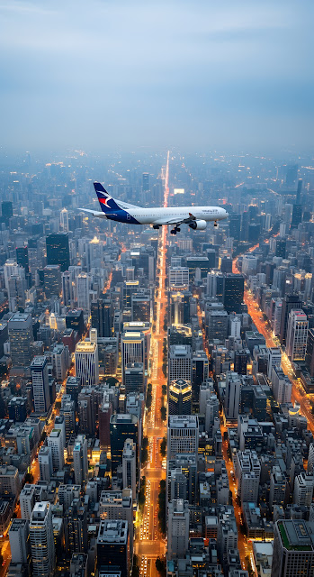 Commercial Airplane Flying Over Illuminated City Skyline Dusk - Free mobile Wallpaper
