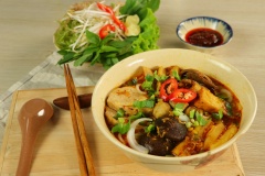 Cho bún ra tô, cho phần topping lên trên, rắc thêm ngò gai và hành tây lên mặt, sau đó chan phần nước lèo lên là hoàn tất. Món ăn dùng kèm với ớt xắt lát, chanh và rau sống.