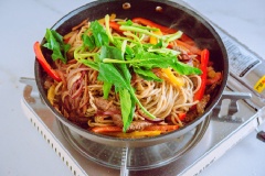Thêm ớt chuông, hành tây, cả bó xôi và mì vào đảo đều cho nguyên liệu chín là xong.