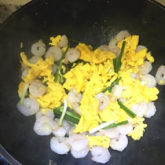 Phi thơm tỏi băm với 1 muỗng canh dầu ăn, cho tôm nõn vào đảo cho săn lại. Khi tôm chín, cho trứng vào đảo đều. Cho hành lá cắt khúc ngắn vào xào cùng. Nêm 1g muối, xào tiếp cho ngấm gia vị, tắt bếp.
