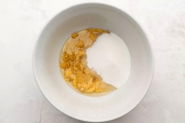 Olio e zucchero aggiunti alle banane schiacciate nella ciotola
