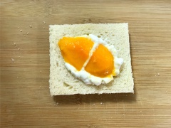 Gọt vỏ xoài, thái thịt xoài thành những miếng mỏng và nhỏ. Cắt bỏ rìa các lát bánh mì sandwich. Phết sữa chua lên trên một lát bánh mì sandwich rồi xếp các miếng xoài chín lên, sau cùng phết sữa chua rồi đặt lát bánh mì sandwich khá khít lên trên. Làm tương tự cho chiếc bánh còn lại.