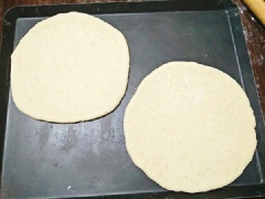 Rắc bột khô lên bàn sạch, lấy khối bột ra bàn và ấn xẹp bọt khí, dùng cây cán bột cán thành hình tròn vừa mỏng. Dùng dĩa xăm đều lên mặt bánh để khi nướng bánh không bị phồng lên, cho đế bánh vào khuôn pizza hoặc khay nướng, quét 1 lớp mỏng dầu ăn lên mặt bánh, đưa vào lò nướng ở nhiệt độ 200 độ C, nướng sơ qua 5-10 phút thì lấy ra, vậy là xong phần đế bánh rồi nhé!