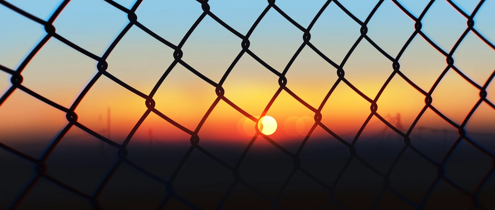 Sunset Through Chain Link Fence - High Contrast Photography 4K Wallpaper (5640x2400)