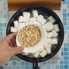 Mở lửa vừa, làm nóng chảo, cho bơ lạt vào nấu chảy. Cho 1/4 muỗng cà phê muối vào và khuấy tan. Sau đó, cho kẹo marshmallow, sữa bột và đậu phộng rang vào chảo bơ. Khuấy đều và nấu đến khi kẹo dẻo chảy mềm là được.