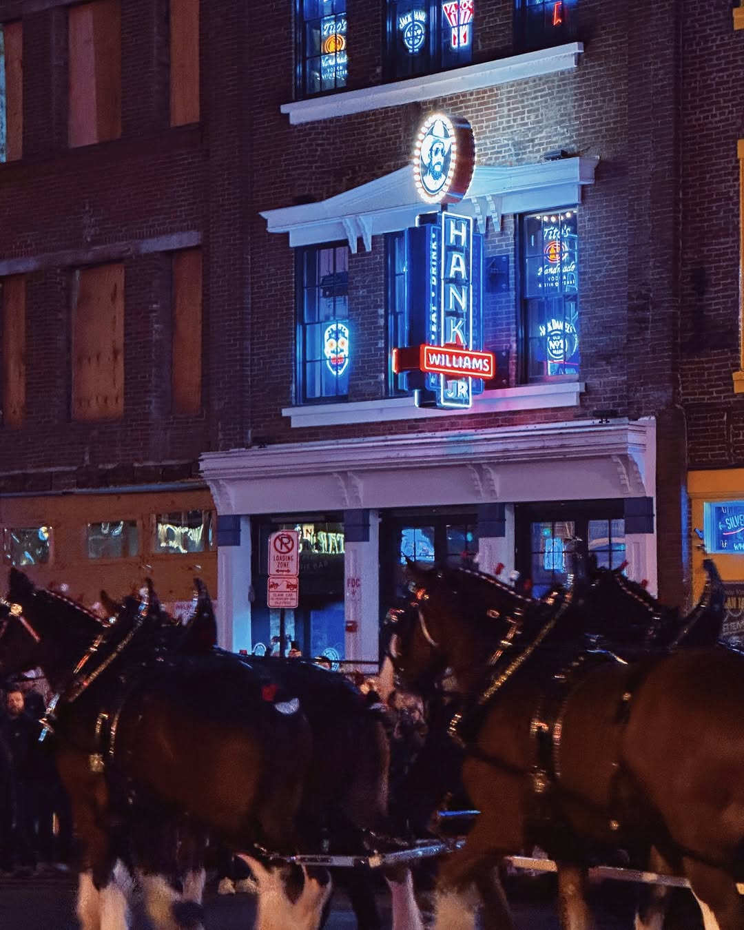 Exterior shot of Hank Williams Jr.'s Boogie Bar with bright signage and a lively crowd.