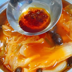 Bắc nồi lên bếp, đợi nước hơi sủi bọt thì cho nấm vào trước, nấu đến khi sôi bùng. Cho kim chi vào khoảng 2 phút sau đó tắt bếp và nêm cùng 2 muỗng hạt nêm Knorr nấm hương. Có thể cho thêm sa tế hoặc tương ớt Hàn Quốc tùy theo khẩu vị cay hay không.