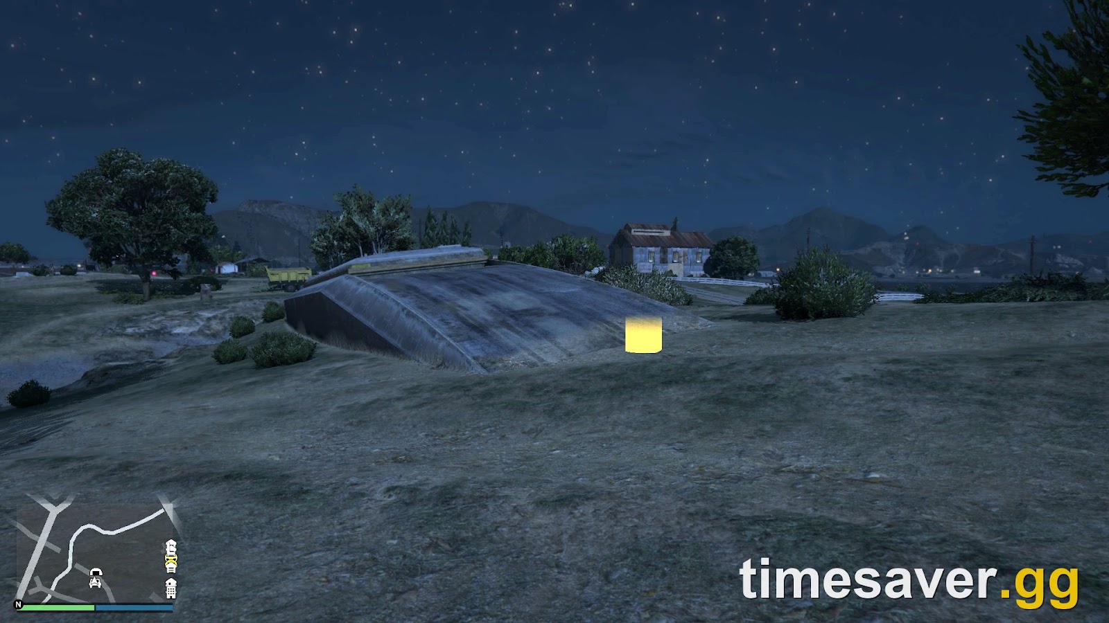 The Grapeseed Bunker entrance hatch glowing on a grass hillside in GTA Online, with the farmhouse and Grapeseed fields behind it