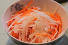 Củ cải trắng, cà rốt rửa sạch, bào vỏ, cắt sợi. Trộn vào chén cà rốt, củ cải trắng 1/4 muỗng cà phê muối, 1 muỗng cà phê đường, 1 muỗng canh giấm, trộn đều. Hành lá rửa sạch, cắt nhỏ.