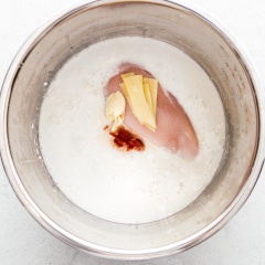 Rửa sạch ức gà. Băm nhỏ tỏi, gừng. Cho nước dùng gà, nước cốt dừa, tương cà ri đỏ Thái Lan, tỏi băm, gừng băm và ức gà đun sôi lên. Trong lúc đợi hỗn hợp sôi, bạn làm sạch ngò rí, hành lá và chanh. Thái miếng chanh. Băm nhỏ hành lá và ngò rí. Nếu bạn thích dùng nhiều topping hơn thì có thể bổ sung thêm số lượng hành, chanh, ngò nhé.