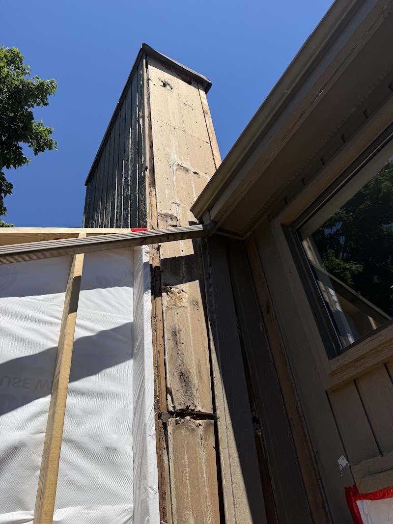 Chimney at The Lookout before repair, weathered siding and failed coating above the roof line