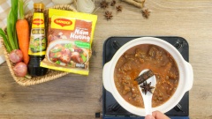 Đun nóng 1 muỗng canh dầu ăn, cho 10gr hành tím băm và 10gr tỏi băm vào phi thơm sau đó cho thịt bò đã ướp vào xào săn. Lúc này cho sốt cà cô đặc vào đảo đều cùng thịt bò rồi chế nước sấm sấp mặt thịt. Đun sôi, hớt sạch bọt trong nồi rồi cho sả, hoa hồi và quế vào. Hạ lửa nhỏ hầm thịt bò 30 phút cho mềm, sau đó vớt hoa hồi và quế ra khỏi nồi.