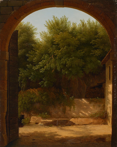 A view of a sunlit courtyard with a trough seen through an archway