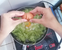 Thấy khổ qua chuyển màu trong xanh thì đập 2 quả trứng cho vào chảo khổ qua. Dùng đũa đảo đều tay cho trứng áo vào quanh khổ qua.