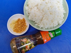 Làm nóng chảo, phi thơm tỏi băm cùng gạo rang sẵn, khi tỏi vừa ngả vàng thì cho cơm vào tán đều.