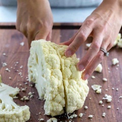 Làm nóng lò ở 400 độ F (200 độ C). Bông cải trắng ngâm nước muối, rửa sạch, để ráo. 1 cây bông cải trắng cắt thành 4 lát. Trộn bột tỏi, ớt bột, muối, ngò rí băm và tiêu với nhau.