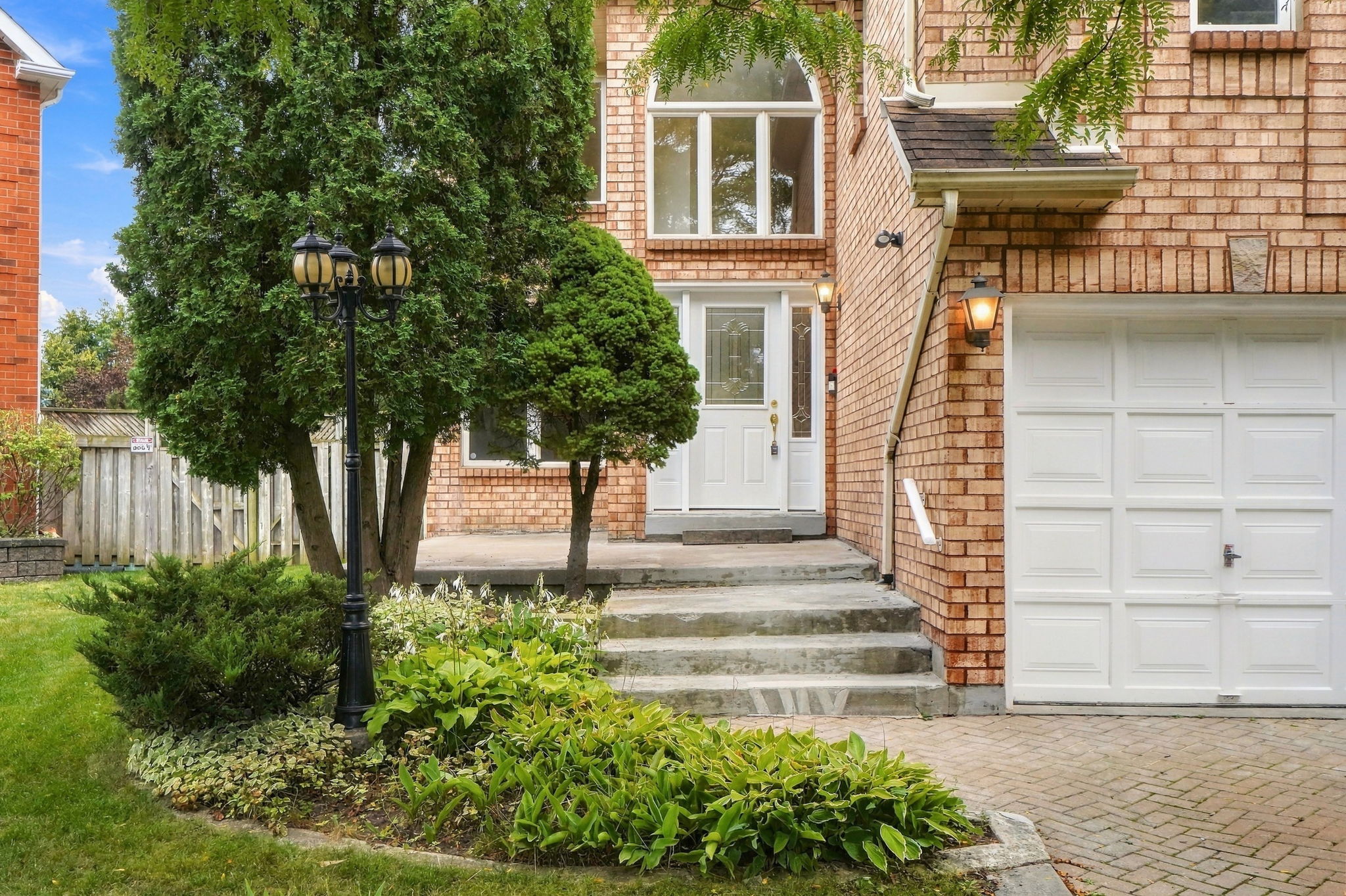 The front door and garage, with evergreens and a lamp post