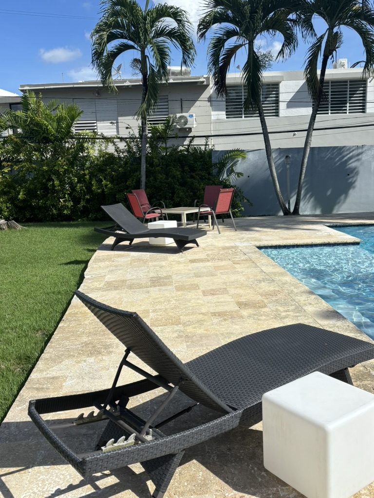 Poolside lounge seating under palm trees at The Palatial Retreat