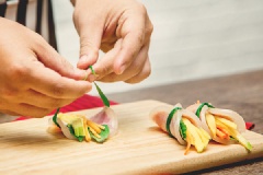 Cuốn xoài, cà rốt và vài lá húng quế lại bằng lát thịt, cột ngang bằng hành lá đã chần qua nước sôi.